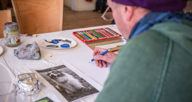 Ein Mann zeichnet einen Hund bei einem Kunstworkshop für obdachlose Menschen